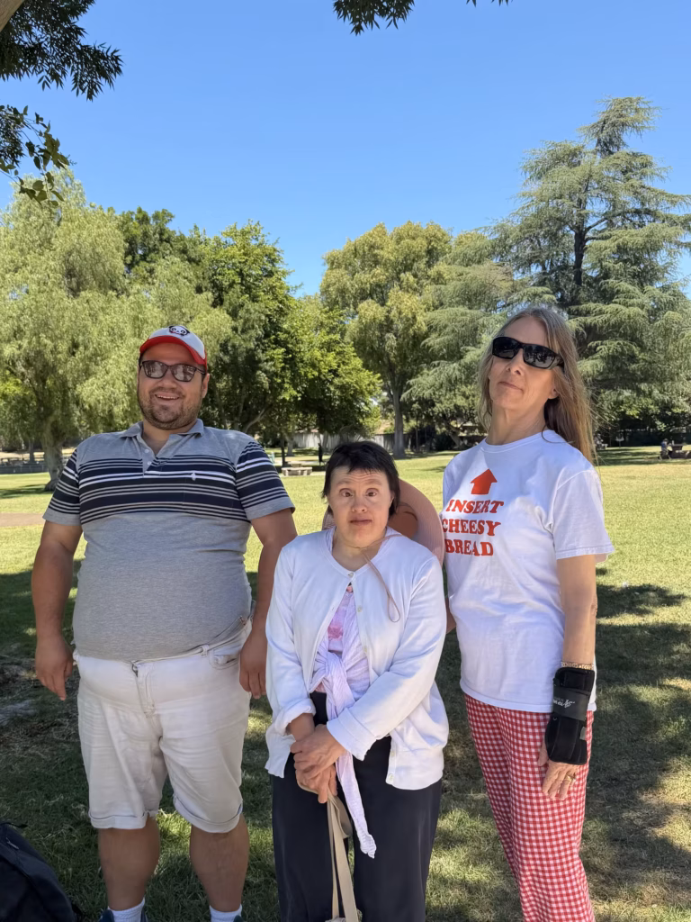 Three Compass participants standing together in a park